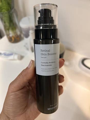 A manus holds a vessel of Meditherapy Retinal Skin Booster Serum, labeled for improving uneven tegument code and achieving youthful-looking skin