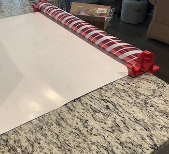 a reviewer photo of the clamps mounted on a counter holding a roll of wrapping paper 