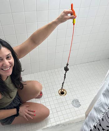reviewer holding the hair-filled flexisnake over a shower drain