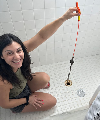 reviewer holding the hair-filled flexisnake over a shower drain