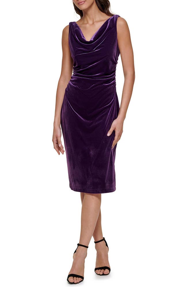 Person in a stylish velvet dress with a draped neckline and knee-length cut, wearing ankle-strap heels