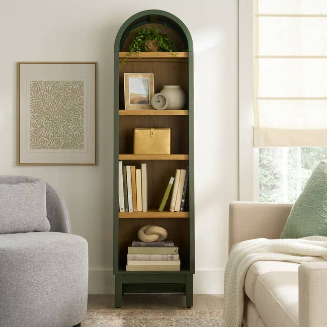 Tall, arched bookshelf with decor items and books, placed successful  a cozy surviving  country   country   with a sofa and window