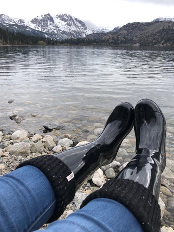 a reviewer in black ugg rain boots