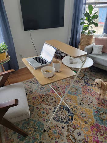 Laptop on a portable stand over a sofa, with snacks nearby, indicating a home office setup for comfort and productivity
