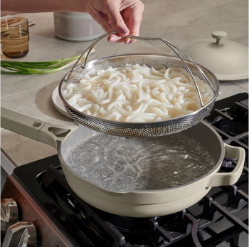 noodles being strained over grey Always Pan filled with water
