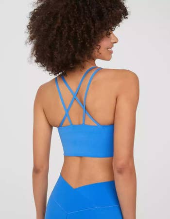 a model in a cobalt blue sports bra with a strappy criss-cross back