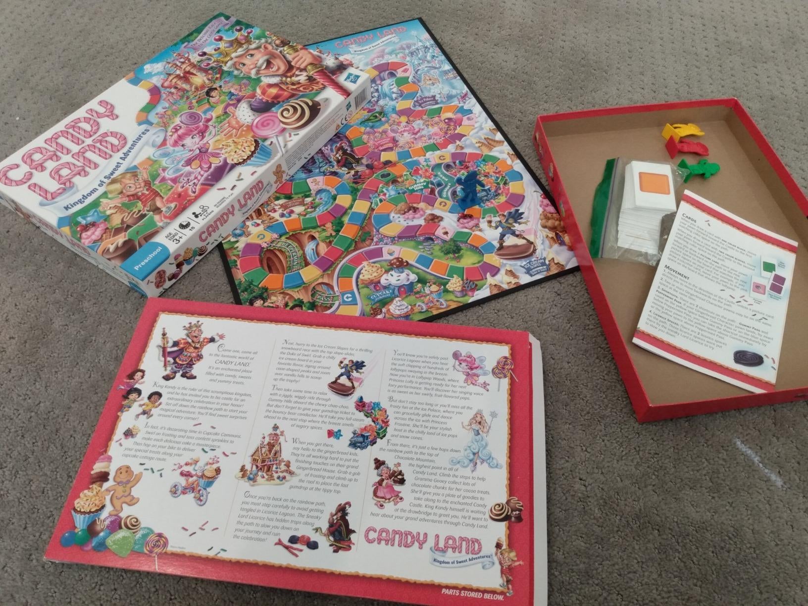 Reviewer image of Candy Land game board, game pieces, and instructions on carpet