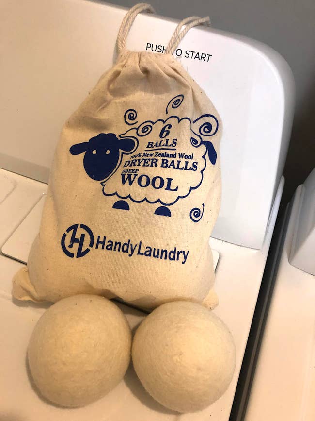 photo of two wool balls sitting on top of dryer in front of wool ball bag