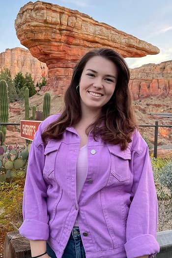 reviewer posing wearing the purple jean jacket
