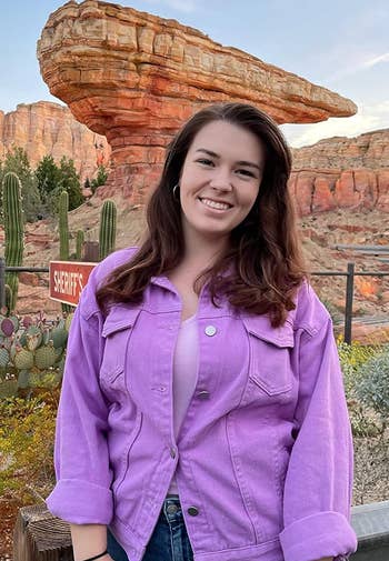 reviewer posing wearing the purple jean jacket