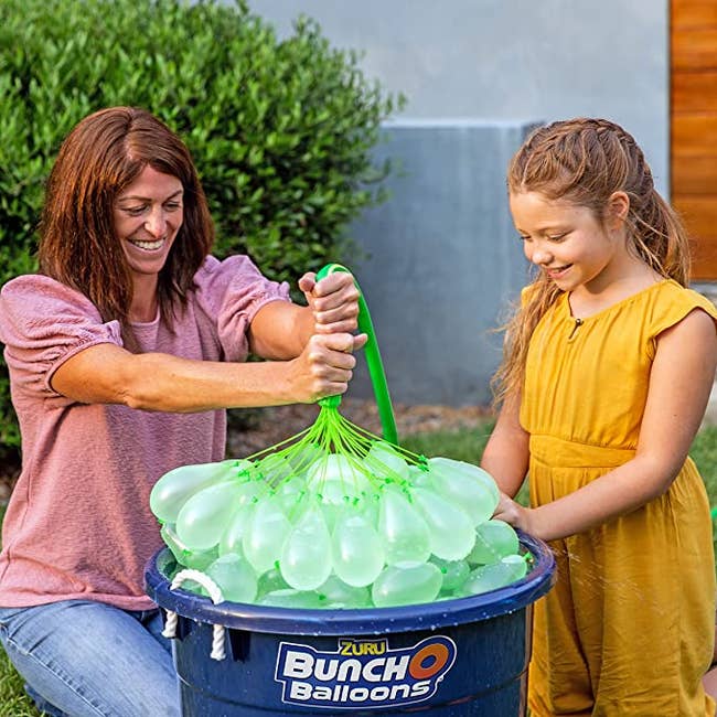 adult and child filling a bunch of water balloons at one time