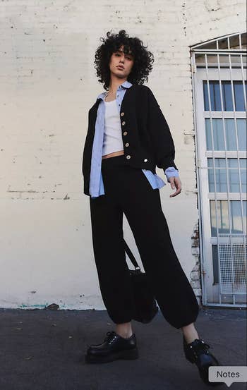  a cardigan implicit    a garment  with escaped   pants and chunky shoes, lasting  against a ceramic  wall