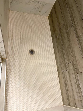 same reviewer showing their shower looking brand new after using the tile cleaner