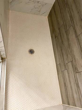same reviewer showing their shower looking brand new after using the tile cleaner