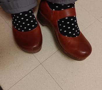 a reviewer wearing the clogs in burgundy with polka dot socks