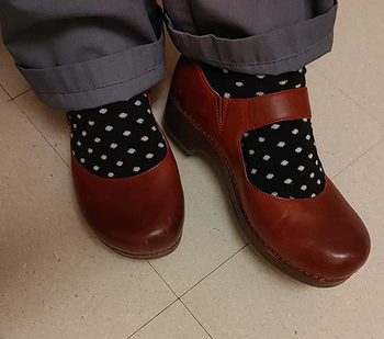 a reviewer wearing the clogs in burgundy with polka dot socks