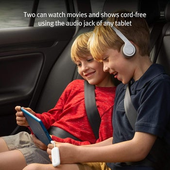child models watching something together on one tablet with the AirFly plugged in so they can both hear through their headphones
