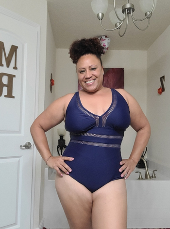 reviewer in navy v neck bathing suit with stripes of see through mesh