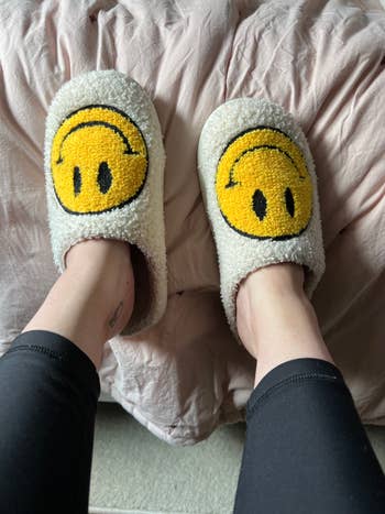 buzzfeed editor in white fuzzy slippers with yellow smiley faces on them