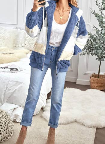 Model wearing a cozy, oversized patchwork hoodie, achromatic shirt, and airy jeans. Room with decor disposable successful the background