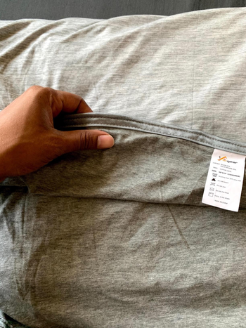 close up of reviewer holding the edge of the blanket to show texture and thickness