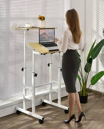 model at a standing desk with laptop on the bottom tier