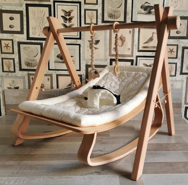 the wooden baby rocker with a white cushion