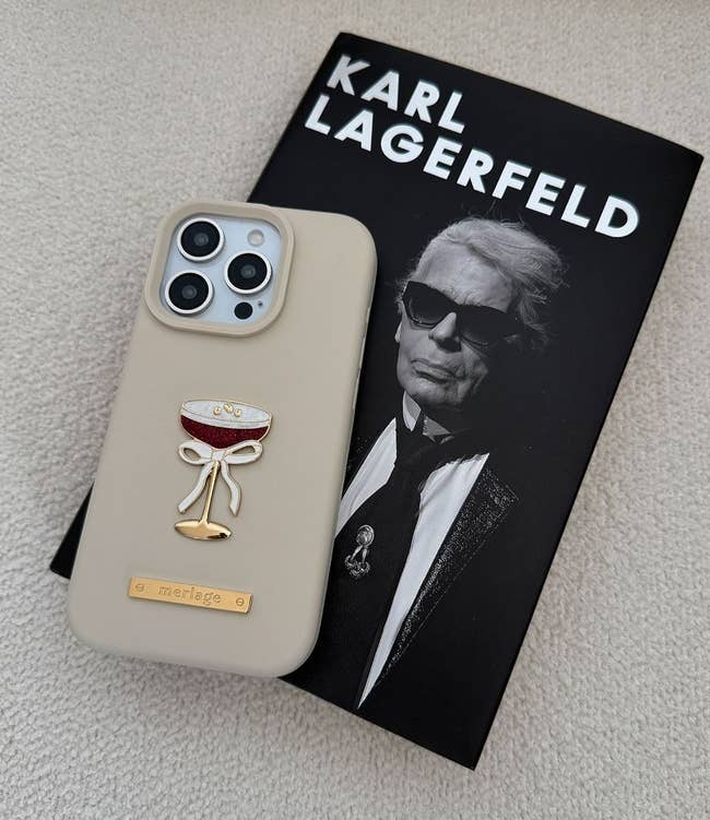 Phone case with champagne glass design on a Karl Lagerfeld book, suggesting luxury accessory shopping