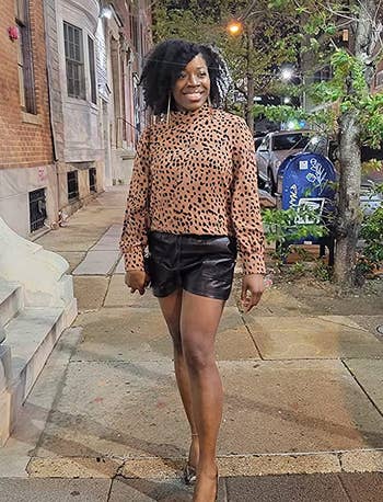 reviewer wearing the black shorts with a leopard print top and heels