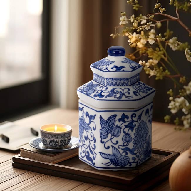 Ceramic jar with intricate patterns next to a small candle on a table