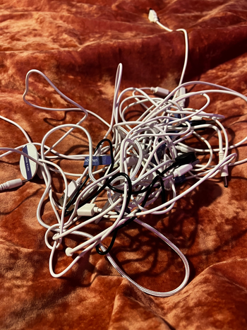 on left, tangled cord wires on top of velvet blanket
