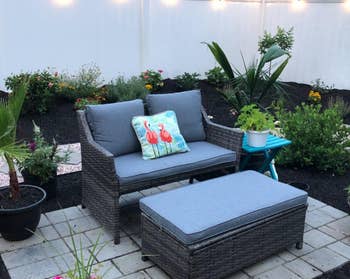 reviewer's gray coffee table and loveseat set with blue cushions in a backyard 