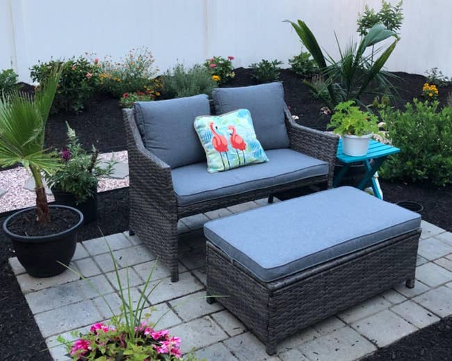 reviewer's gray coffee table and loveseat set with blue cushions in a backyard