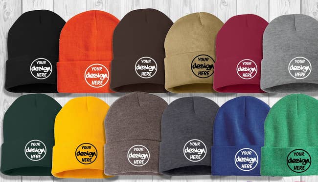 Two rows of knit beanies in black, orange, brown, maroon, gray, green, yellow, and blue with circular embroidery that reads 