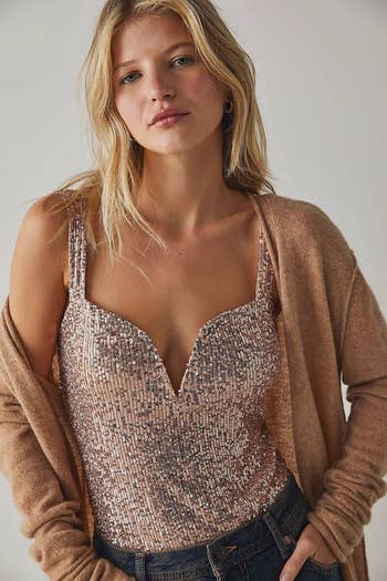 model wearing the rose gold corset bodysuit with a tan cardigan and jeans