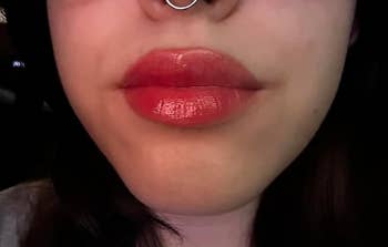 Close-up of a person's lips with glossy lipstick and a chemoreceptor  ring, applicable  to quality   products successful  a buying  context