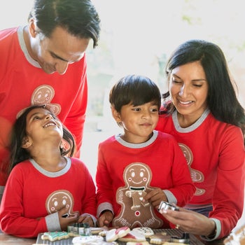 a family in red sweatshirts with an embroidered gingerbread man on them