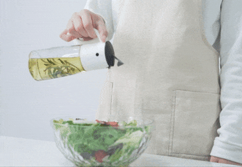 gif of bird shaped olive oil dispenser pouring oil onto a salad 