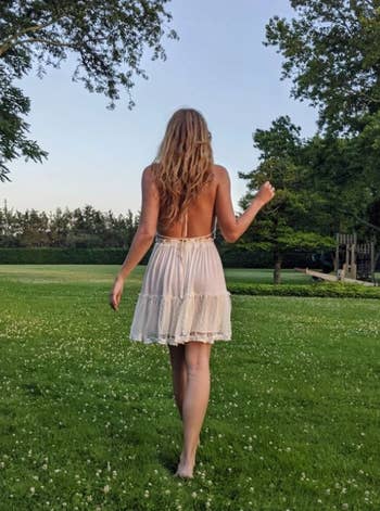 Reviewer walking on grass, wearing backless summer dress