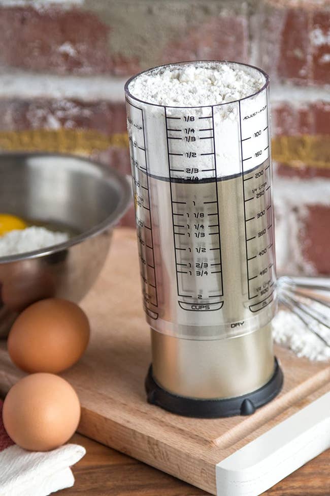 An adjustable measuring cup filled with flour
