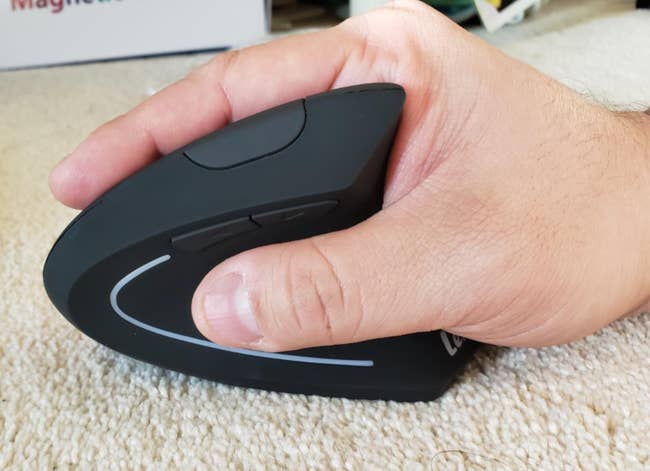 Reviewer using black mouse with grooves keeping their thumb on side and fingers on top 