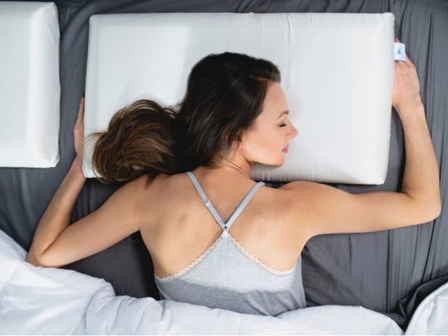 model lying on their stomach with their head on a rectangle white pillow