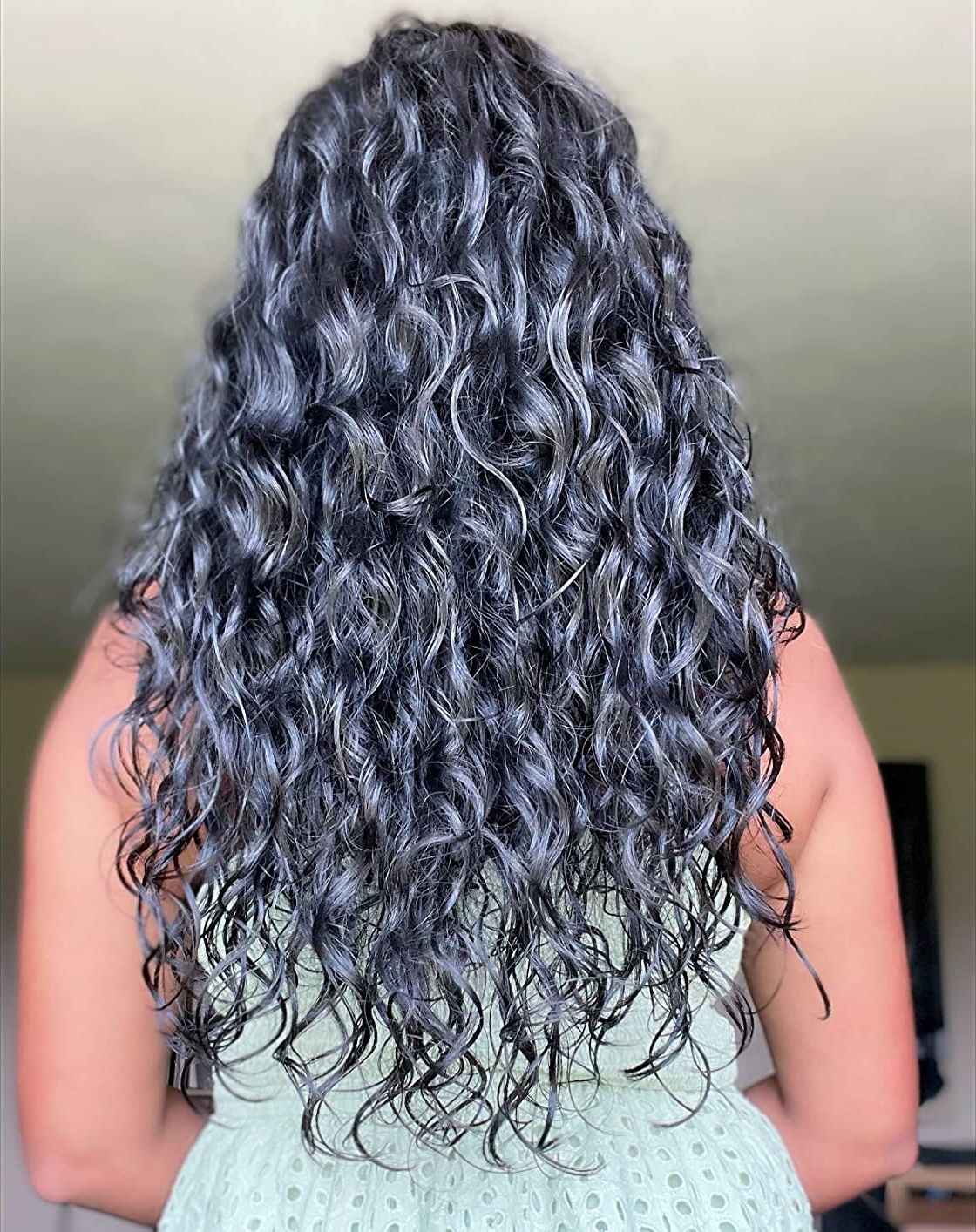 image of reviewer with long dark curly hair with no frizz and a natural looking sheen