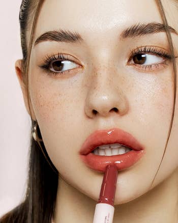 Person applying lipstick portion    looking away, showcasing a glossy finish