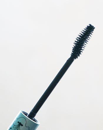 mascara wand with blue handle coated in black mascara