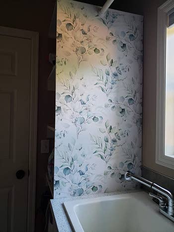reviewer photo of the soft bluish floral wallpaper on a wall next to a sink
