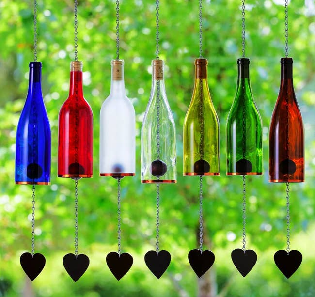 Wine bottle wind chimes in various colors hanging near a window