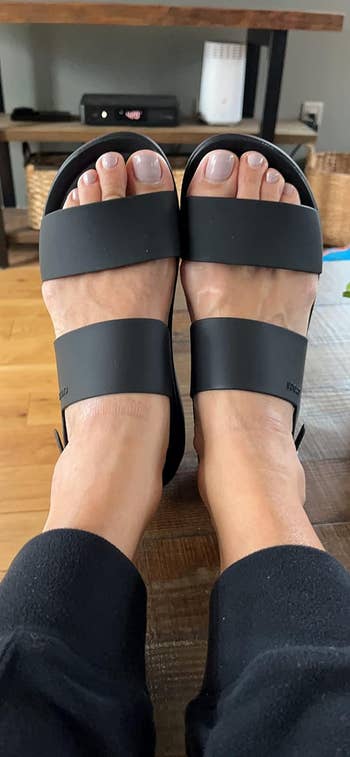 reviewer wearing black slide sandals with two straps, alongside an article about shopping for footwear