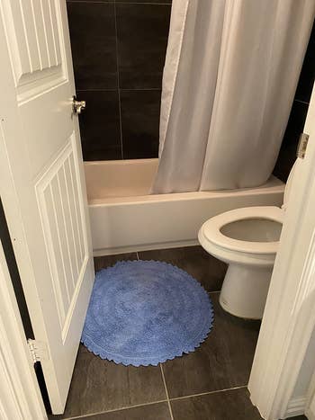 reviewer photo of the round blue bath mat in their bathroom
