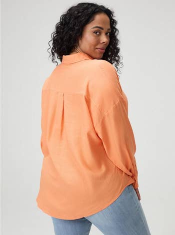 Person wearing a loose, long-sleeve garment successful a casual style, looking implicit their shoulder, paired with bluish jeans
